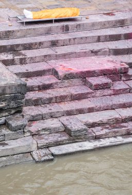 Katmandu, Nepal, 10-03-2023: Kutsal Bagmati nehri boyunca bir sedyede yıkanmış ve bandajlanmış bir ceset, Pashupatinath Tapınağı 'nda yakma töreni, Shiva' ya adanmış ünlü Hindu tapınağı.