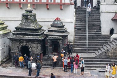 Kathmandu, Nepal, 10-03-2023: Kutsal Bagmati nehri boyunca bir sedyede yıkanmış ve bandajlanmış bir aile, Pashupatinath Tapınağı 'nda yakma töreni, Shiva' ya adanmış Hindu tapınağı