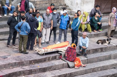 Kathmandu, Nepal, 10-03-2023: Kutsal Bagmati nehri boyunca bir sedyede yıkanmış ve bandajlanmış bir aile, Pashupatinath Tapınağı 'nda yakma töreni, Shiva' ya adanmış Hindu tapınağı