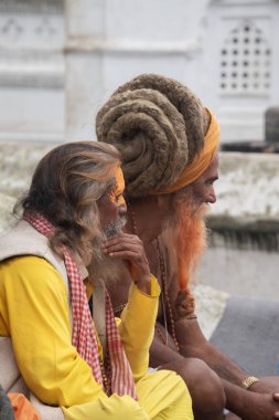 Katmandu, Nepal, 10-03-2023: Hindu gurular kutsal Bagmati nehri boyunca ölüler için hediyeler hazırlamayı bekliyorlar, Pashupatinath Tapınağı 'nda yakma töreni, Shiva' ya adanmış Hindu tapınağı.