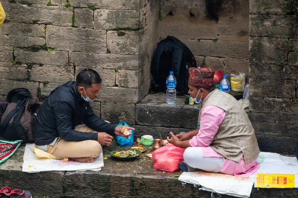 Katmandu, Nepal, 10-03-2023: Brahmin ile birlikte kutsal Bagmati nehrinin kıyısında dua eden akrabalar, Pashupatinath Tapınağı 'nda yakma töreni, Shiva' ya adanmış ünlü Hindu tapınağı.