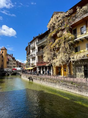 Annecy, Haute-Savoie, Fransa, 04-21-2024: Eski kasabadaki bir binanın üzerindeki dev beyaz salkım, Thiou Nehri 'nin kristal berrak suları ve Fransız Venedik' inin kanallarından biriyle ufuk çizgisi