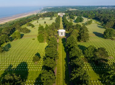 Aerial view of the Normandy American Cemetery and Memorial is a World War II cemetery and memorial in Colleville-sur-Mer, Normandy, France. White cross on a green lawn clipart