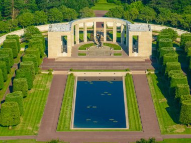 Aerial view of the Normandy American Cemetery and Memorial is a World War II cemetery and memorial in Colleville-sur-Mer, Normandy, France. White cross on a green lawn clipart