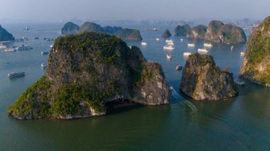 Halong Körfezi 'nin havadan görünüşü, UNESCO Dünya Mirası Bölgesi ve Quang Ninh, Vietnam' da popüler bir seyahat merkezidir. Körfezde dönüşümlü olarak seyahat eden gemiler ve adalar. Gün batımı