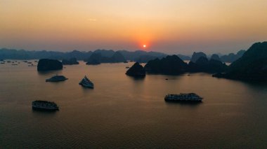 Halong Körfezi 'nin havadan görünüşü, UNESCO Dünya Mirası Bölgesi ve Quang Ninh, Vietnam' da popüler bir seyahat merkezidir. Körfezde dönüşümlü olarak seyahat eden gemiler ve adalar. Gün batımı