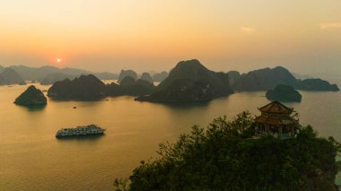 Halong Körfezi 'nin havadan görünüşü, UNESCO Dünya Mirası Bölgesi ve Quang Ninh, Vietnam' da popüler bir seyahat merkezidir. Körfezde dönüşümlü olarak seyahat eden gemiler ve adalar. Gün batımı