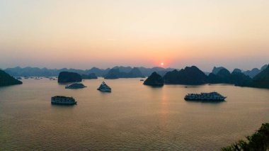 Halong Körfezi 'nin havadan görünüşü, UNESCO Dünya Mirası Bölgesi ve Quang Ninh, Vietnam' da popüler bir seyahat merkezidir. Körfezde dönüşümlü olarak seyahat eden gemiler ve adalar. Gün batımı