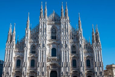Milano Katedrali ve meydan manzarası. Duomo di Milano. Katedralin ön cephesine beyaz mermerden bir göz atın. Buttresses, pinnacles ve spiers. Madonnina Heykeli. Lombardia 'da. İtalya