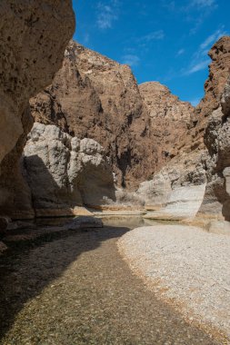 Umman, Ortadoğu, 03-25-2025: Wadi Shab, kristal berrak su havuzlarının ve bir mağaranın içindeki gizli şelalenin bulunduğu dar bir kanyon, Hajar Dağları 'nın doğusundan Umman Körfezi' ne akıyor.