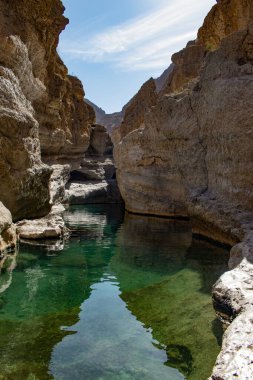Umman, Ortadoğu, 03-25-2025: Wadi Shab, kristal berrak su havuzlarının ve bir mağaranın içindeki gizli şelalenin bulunduğu dar bir kanyon, Hajar Dağları 'nın doğusundan Umman Körfezi' ne akıyor.