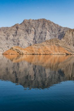 Umman, Ortadoğu: Benzersiz çöl fiyortlarıyla Norveç olarak bilinen Musandam Yarımadası 'nda seyreden Hürmüz Boğazı' nın sakin sularındaki bir ayna gibi dağ yansıması.