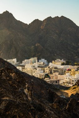 Umman, Orta Doğu, 03-09-2025: Başkent Muscat yakınlarındaki küçük geleneksel balıkçı ve tekne yapımcılarından oluşan Kantab 'daki dağların arasından süzülen ışık ile çarpıcı bir gün batımı.