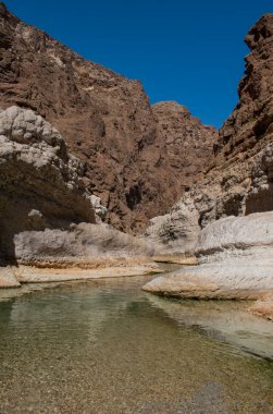 Umman, Ortadoğu, 03-25-2025: Wadi Shab, kristal berrak su havuzlarının ve bir mağaranın içindeki gizli şelalenin bulunduğu dar bir kanyon, Hajar Dağları 'nın doğusundan Umman Körfezi' ne akıyor.