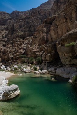 Umman, Ortadoğu, 03-25-2025: Wadi Shab, kristal berrak su havuzlarının ve bir mağaranın içindeki gizli şelalenin bulunduğu dar bir kanyon, Hajar Dağları 'nın doğusundan Umman Körfezi' ne akıyor.