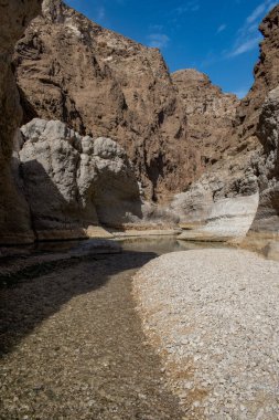 Umman, Ortadoğu, 03-25-2025: Wadi Shab, kristal berrak su havuzlarının ve bir mağaranın içindeki gizli şelalenin bulunduğu dar bir kanyon, Hajar Dağları 'nın doğusundan Umman Körfezi' ne akıyor.