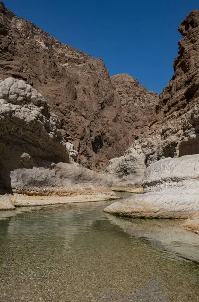 Umman, Ortadoğu, 03-25-2025: Wadi Shab, kristal berrak su havuzlarının ve bir mağaranın içindeki gizli şelalenin bulunduğu dar bir kanyon, Hajar Dağları 'nın doğusundan Umman Körfezi' ne akıyor.