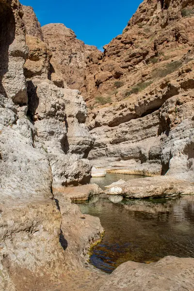 Umman, Ortadoğu, 03-25-2025: Wadi Shab, kristal berrak su havuzlarının ve bir mağaranın içindeki gizli şelalenin bulunduğu dar bir kanyon, Hajar Dağları 'nın doğusundan Umman Körfezi' ne akıyor.