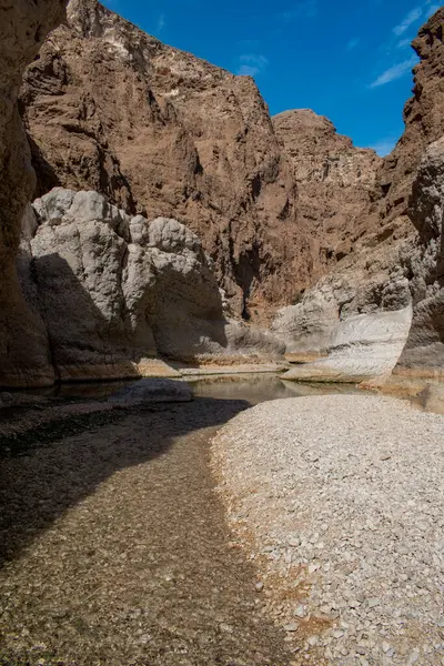 Umman, Ortadoğu, 03-25-2025: Wadi Shab, kristal berrak su havuzlarının ve bir mağaranın içindeki gizli şelalenin bulunduğu dar bir kanyon, Hajar Dağları 'nın doğusundan Umman Körfezi' ne akıyor.