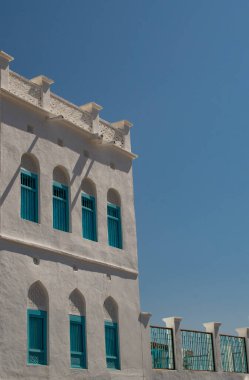 Umman, Orta Doğu: Mutrah Corniche 'de mavi pencereli beyaz ev, Eski Muscat' ın tipik silueti, orijinal tarihi şehir Muscat, Umman Körfezi kıyısındaki Umman 'ın başkenti.