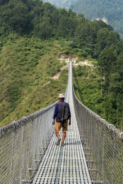Nepal, Asya: Gandaki bölgesindeki Kushma 'daki Tindobate-Pelakot Askı Köprüsü' nde yürüyen nepalli bir adam, Nepal 'in en uzun ve en uzun asma köprülerinden biri, muhteşem manzaralarıyla bilinen popüler turistik cazibesi