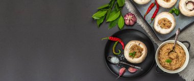 Çiğ mantar kapları pişirmeye hazır. Taze şampiyonlar, baharatlar, sebzeler. Yemek pişirme süreci, modaya uygun sert ışık, karanlık gölge. Siyah taş arkaplan, pankart biçimi