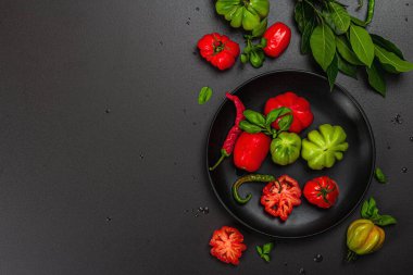 Yeşil ve kırmızı kurdeleli domates, Amerikan ya da Floransa usulü. Olgun sebzeler, acı biber, taze defne yaprakları. Modaya uygun sert ışık, koyu gölge, taş beton zemin, düz zemin, üst manzara