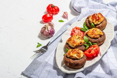 Pişmiş mantar kapları yenmeye hazır. Şampiyonlar, baharatlar, sebzeler, peynir. Hizmet edilen bölüm, modaya uygun sert ışık, karanlık gölge. Beyaz alçı arkaplan, kopyalama alanı