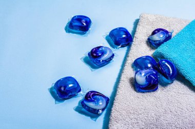 Makine yıkama konsepti. Deterjanlı kapsüller, yumuşak havlular, kış tazeliği. Çamaşır kapsülleri, sıvı renkli jel. Çevre dostu giysiler yıkama, düz yatak. Mavi arkaplan, boşluğu kopyala