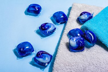 Makine yıkama konsepti. Deterjanlı kapsüller, yumuşak havlular, kış tazeliği. Çamaşır kapsülleri, sıvı renkli jel. Çevre dostu giysiler yıkama, düz yatak. Mavi arkaplan, kapat