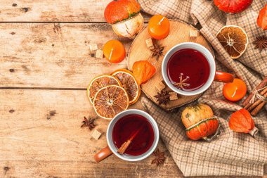 Baharatlı sıcak çay. Sonbahar neşesi, geleneksel sonbahar içeceği. Balkabağı, eşarp, mumlar, yıldız anason, tarçın. Tahta kaplama arka plan, üst görünüm