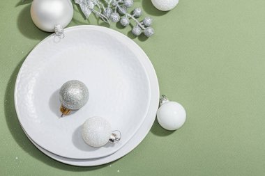 Boş seramik tabaklar ve modaya uygun Savannah Green renk arka planında geleneksel aksesuarlar. Şenlikli Yeni Yıl çatal bıçak takımı, sert ışık, koyu gölge, düz yer, üst manzara