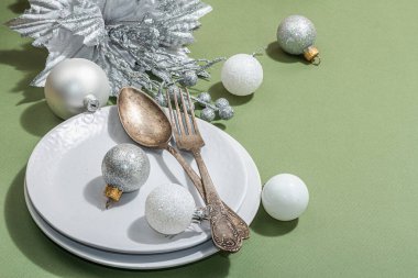 Boş seramik tabaklar ve modaya uygun Savannah Green renk arka planında geleneksel aksesuarlar. Şenlikli Yeni Yıl çatal bıçak takımı, sert ışık, karanlık gölge, düz yer, kopyalama alanı