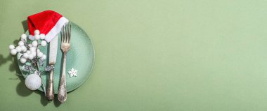 Boş seramik tabaklar ve modaya uygun Savannah Green renk arka planında geleneksel aksesuarlar. Şenlikli Yeni Yıl çatal bıçak takımı, sert ışık, koyu gölge, düz döşeme, afiş biçimi