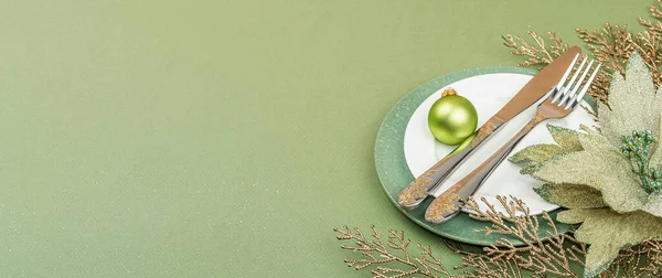 Stock image Christmas table setting with empty ceramic plates, traditional accessories on trendy Savannah Green color background. Festive New Year cutlery, flat lay, banner format