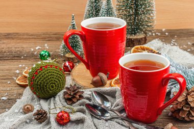 Sıcak çay ve geleneksel Noel süsüsüyle kış kompozisyonu. Yeni yıl baloları, köknar ağaçları, portakallar ve kozalaklar. Rustik biçim, eski ahşap arkaplan, kopyalama alanı