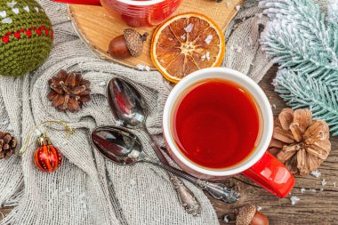 Sıcak çay ve geleneksel Noel süsüsüyle kış kompozisyonu. Yeni yıl baloları, köknar ağaçları, portakallar ve kozalaklar. Kırsal stil, eski ahşap arkaplan, üst manzara