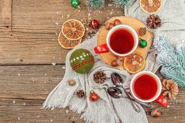 Sıcak çay ve geleneksel Noel süsüsüyle kış kompozisyonu. Yeni yıl baloları, köknar ağaçları, portakallar ve kozalaklar. Kırsal stil, eski ahşap arkaplan, üst manzara