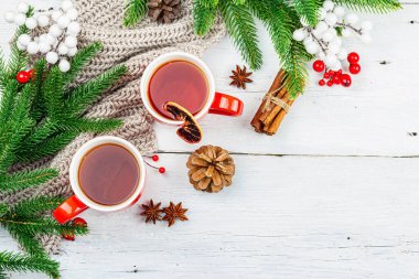 Sıcak kış ya da seramik kırmızı bardaklarda Noel çayı. Firavun ağacı dalları, limon dilimleri, baharatlar ve meyveler. Geleneksel Yeni Yıl dekorasyonu, beyaz ahşap arka plan, üst görünüm