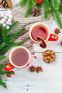 Sıcak kış ya da seramik kırmızı bardaklarda Noel çayı. Firavun ağacı dalları, limon dilimleri, baharatlar ve meyveler. Geleneksel Yeni Yıl dekorasyonu, beyaz ahşap arka plan, üst görünüm