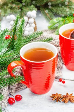 Sıcak kış ya da seramik kırmızı bardaklarda Noel çayı. Firavun ağacı dalları, limon dilimleri, baharatlar ve meyveler. Geleneksel Yeni Yıl dekorasyonu, beyaz ahşap arka plan, kapat