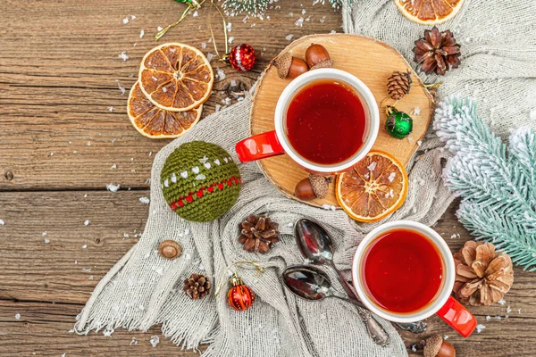 stock image Winter cozy composition with hot tea and traditional Christmas decoration. New Year balls, fir trees, oranges and pine cones. Rustic style, old wooden background, top view