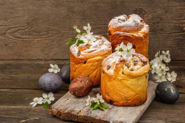 Paskalya pastası Cruffin 'i ya da boyalı yumurtalı tatlı ekmek kulich' i. Geleneksel şenlikli pişirme ve taze kiraz çiçekleri, şenlikli ahşap arka plan. Vintage panolar, rustik biçim, kopyalama alanı