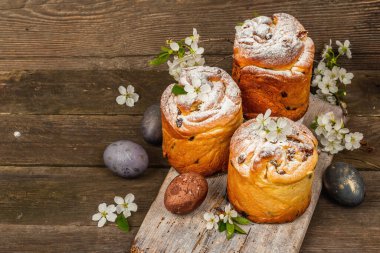 Paskalya pastası Cruffin 'i ya da boyalı yumurtalı tatlı ekmek kulich' i. Geleneksel şenlikli pişirme ve taze kiraz çiçekleri, şenlikli ahşap arka plan. Vintage panolar, rustik biçim, kopyalama alanı
