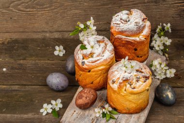 Paskalya pastası Cruffin 'i ya da boyalı yumurtalı tatlı ekmek kulich' i. Geleneksel şenlikli pişirme ve taze kiraz çiçekleri, şenlikli ahşap arka plan. Vintage panolar, rustik biçim, kopyalama alanı
