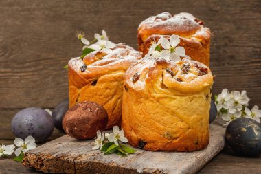 Paskalya pastası Cruffin 'i ya da boyalı yumurtalı tatlı ekmek kulich' i. Geleneksel şenlikli pişirme ve taze kiraz çiçekleri, şenlikli ahşap arka plan. Vintage panolar, rustik biçim, kopyalama alanı