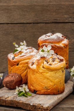 Paskalya pastası Cruffin 'i ya da boyalı yumurtalı tatlı ekmek kulich' i. Geleneksel şenlikli pişirme ve taze kiraz çiçekleri, şenlikli ahşap arka plan. Antika tahtalar, köy tarzı, yakın çekim.