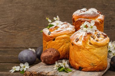 Paskalya pastası Cruffin 'i ya da boyalı yumurtalı tatlı ekmek kulich' i. Geleneksel şenlikli pişirme ve taze kiraz çiçekleri, şenlikli ahşap arka plan. Vintage panolar, rustik biçim, kopyalama alanı