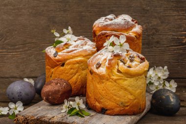 Paskalya pastası Cruffin 'i ya da boyalı yumurtalı tatlı ekmek kulich' i. Geleneksel şenlikli pişirme ve taze kiraz çiçekleri, şenlikli ahşap arka plan. Vintage panolar, rustik biçim, kopyalama alanı