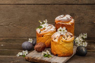 Paskalya pastası Cruffin 'i ya da boyalı yumurtalı tatlı ekmek kulich' i. Geleneksel şenlikli pişirme ve taze kiraz çiçekleri, şenlikli ahşap arka plan. Vintage panolar, rustik biçim, kopyalama alanı